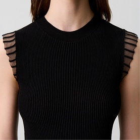 Model wearing Claude Pierlot Rib Knit Top in black, sleeveless with round neck and sheer ruffle detailing at armholes