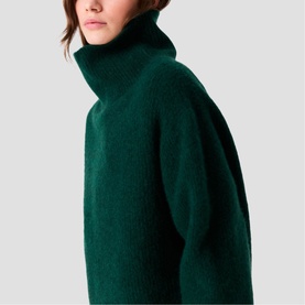 Model wearing Maje bottle green chunky knit turtleneck jumper, close-up detail of ribbed funnel neck