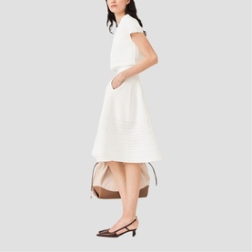 Model wearing Maje metallic white textured midi dress with cap sleeves and full skirt, styled with brown slingback heels and neutral bag