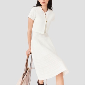 Model wearing Maje metallic white knit co-ord set with cropped top and midi skirt, carrying a nude tote bag.