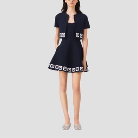 Model wearing Maje navy mini skirt and cropped jacket set with white geometric square embroidered trim detail, styled with silver flat shoes.