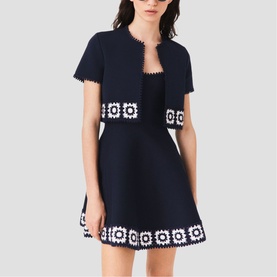 Model wearing Maje navy mini dress with crochet floral trim, paired with matching navy short-sleeve cropped jacket