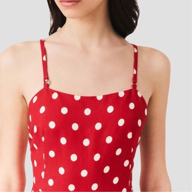 Model wearing Maje Womens French Dress in red dots print, close-up of square neckline and adjustable spaghetti straps