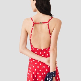 Model wearing Maje Womens French Dress in red polka dot print, showing open back detail with thin straps and gold hardware clasp.