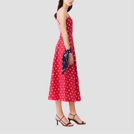 Model wearing Maje French Dress in red dots print midi length with thin straps, styled with black heeled sandals and navy printed clutch.