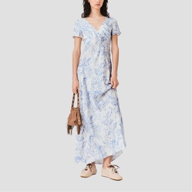 Model wearing Maje French Dress in sky blue large floral print, styled with a tan bag and beige sandals