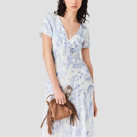 Model wearing Maje French Dress in sky blue large floral print, V-neck, short sleeves, midi length, styled with a brown fringed mini bag.
