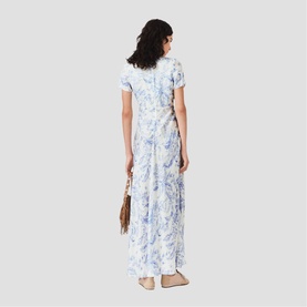 Model wearing Maje Womens French Dress in sky blue large floral print, maxi length, short sleeves, back view, styled with brown fringe bag.