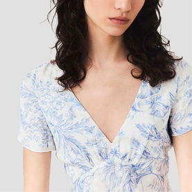 Model wearing Maje Womens French Dress in sky blue large floral print, V-neckline, short puff sleeves, cinched waist detail.