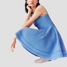 Model wearing Maje Womens French Dress in blue textured knit fit-and-flare silhouette, styled with white woven flat mules