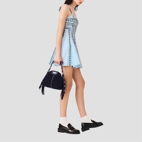 Model wearing Maje Womens French Dress in light blue with stud detailing, styled with a navy suede bag and black loafers