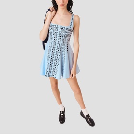 Model wearing Maje Womens French Dress in light blue with black eyelet embroidery, styled with black loafers and a dark shoulder bag.
