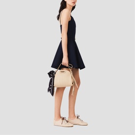 Model wearing Maje Womens French Dress in navy, carrying a cream bucket bag with scarf detail, styled with blush lace-up flats