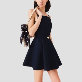 Model wearing Maje Womens French Dress in navy, fit-and-flare silhouette with gold heart buttons, styled with a polka dot bow bag.