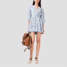 Model wearing Maje sky blue large floral print mini dress with cinched waist, styled with tan leather backpack and lace-up sandals