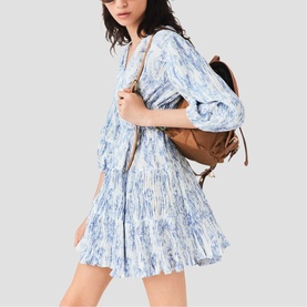 Model wearing Maje sky blue large floral print mini dress with puff sleeves, styled with a tan leather backpack