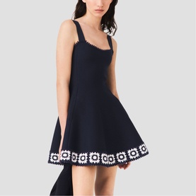 Model wearing Maje Womens French Dress in navy with white daisy crochet trim hem and square neckline, sleeveless fit-and-flare silhouette.