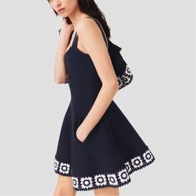 Model wearing Maje Womens French Dress in navy with white floral crochet trim at hem and neckline, sleeveless fit-and-flare silhouette