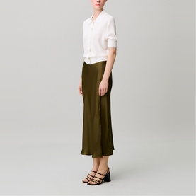 Model wearing Claude Pierlot brown satin midi skirt, styled with a white shirt and black strappy heeled sandals