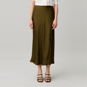 Model wearing Claude Pierlot brown satin midi skirt with flared hem, styled with a white top and black strappy heeled sandals