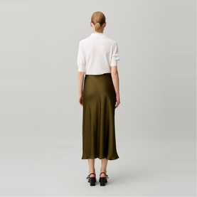 Model wearing Claude Pierlot brown midi skirt, back view, styled with white short-sleeve top and black strappy sandals
