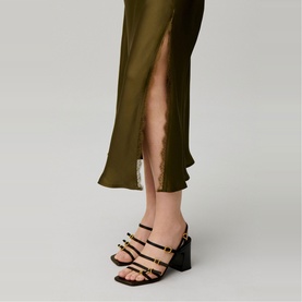 Model wearing Claude Pierlot Womens French Dress in olive green satin with side split, styled with brown strappy block-heel sandals.