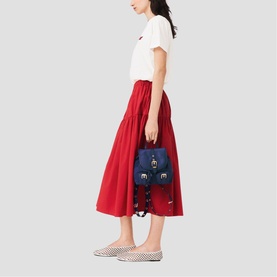 Model carrying Maje bag in metallic blue with gold-tone hardware, styled with white T-shirt, red midi skirt and checked flats.