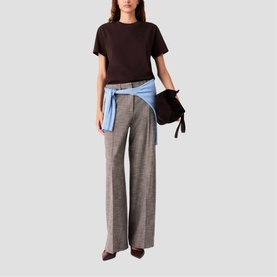 Model wearing Maje dark brown wide-leg trousers with light blue shirt tied at waist, styled with dark brown top and heels.
