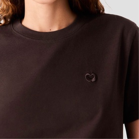 Model wearing Maje dark brown crew neck T-shirt with tonal embroidered heart logo detail at chest