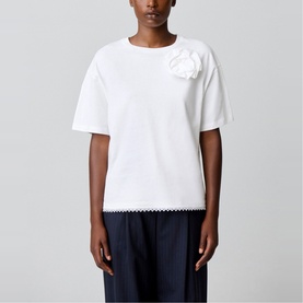 Model wearing Claude Pierlot white short-sleeve T-shirt with 3D floral appliqu&eacute;, styled with navy wide-leg trousers.