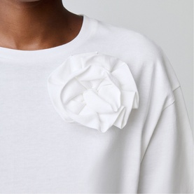 Model wearing Claude Pierlot white sweatshirt with oversized fabric rose corsage detail at chest