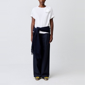 Model wearing Claude Pierlot white floral-appliqu&eacute; T-shirt with wide-leg navy trousers, navy fringed scarf tied at waist, and yellow heeled mules.