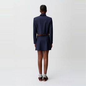 Model wearing Claude Pierlot Cropped Single-Breasted Blazer in blue, back view, styled with a mini skirt and brown belt.