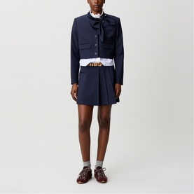 Model wearing Claude Pierlot Cropped Single-Breasted Blazer in blue with removable scarf collar, styled with matching pleated mini skirt and brown