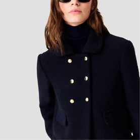 Model wearing Maje navy double-breasted coat with gold buttons and wide lapels, styled with a black roll-neck jumper.