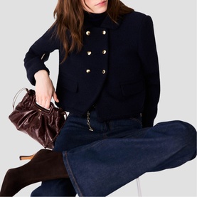 Model wearing Maje navy double-breasted blazer with dark denim wide-leg jeans and brown knee-high boots, carrying burgundy ruched bag.