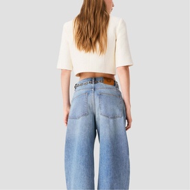 Model wearing light blue wide-leg cropped jeans with cream short-sleeve top, shot from behind showing back pockets and waistband detail