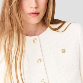 Model wearing cream boucle jacket with gold decorative button fastening, close-up detail view