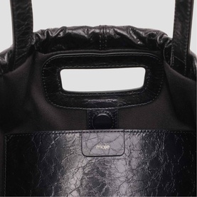 Maje black crinkled leather tote bag, close-up of top handle, snap closure and branded logo detail
