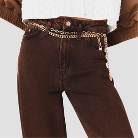 Model with Maje gold chain belt layered at waist, styled with brown wide-leg jeans and cropped white top