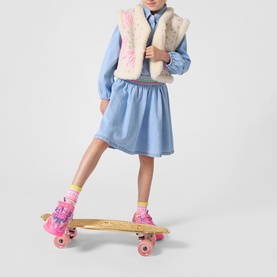 Model wearing Billy Blush dress in bleach blue with fluffy gilet, styled with pink roller skates and yellow socks.
