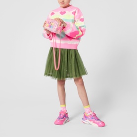 Model wearing Billy Blush multi-coloured heart print knit sweater, styled with green tulle skirt and pink chunky trainers