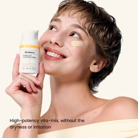 Model with Biodance Day Cream moisturiser held to cheek, white pump bottle, cream swatch visible on skin