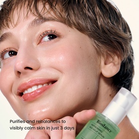 Model with Biodance serum held to cheek, green glass bottle, text overlay reading purifies and rebalances to visibly calm skin in just 3 days