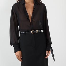 Model with Dehanche Hollyhock Leather Belt in black, gold and silver-tone rounded buckle, worn over black sheer shirt and skirt.