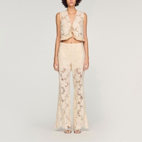 Model wearing Sandro clear floral lace flared trousers with matching sleeveless crop top, full-length front view