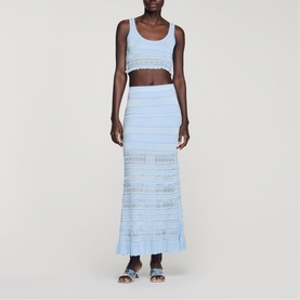 Model wearing Sandro sky blue knit crop top and matching maxi skirt with stripe and open-knit detail, styled with dark sandals.