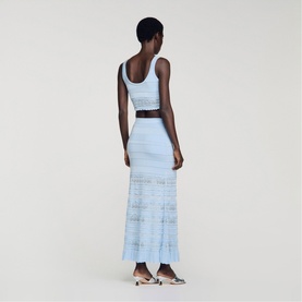 Model wearing Sandro sky blue knit crop top and maxi skirt set with lace panel hem detail, styled with a belt and silver heels