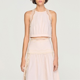 Model wearing Sandro light pink sleeveless crop top with crochet trim detailing, styled with matching tiered midi skirt