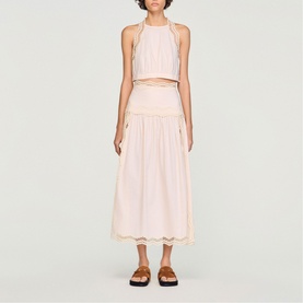 Model wearing Sandro Womens French Dress in light pink, styled as crop top and midi skirt co-ord with scallop hem detail, brown sandals.